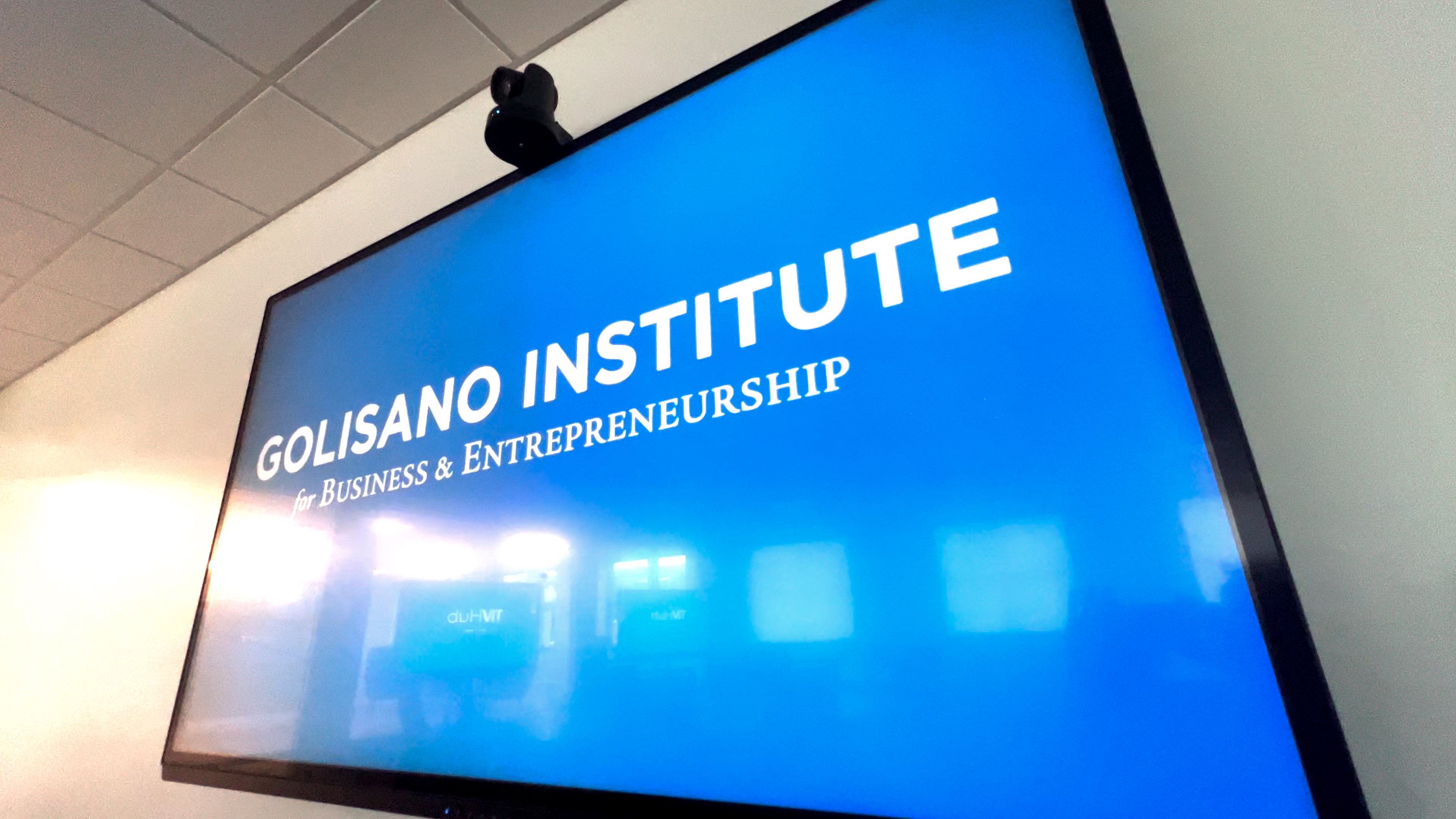 Display showing the Golisano Institute logo, with a webcam at the top supporting hybrid educational technology.